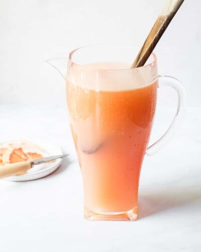 a pitcher of palomas with a wooden spoon sticking out of them