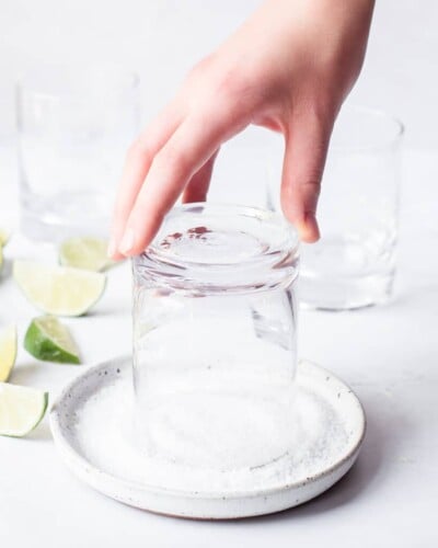 a person holding a glass upside down to salt the rim