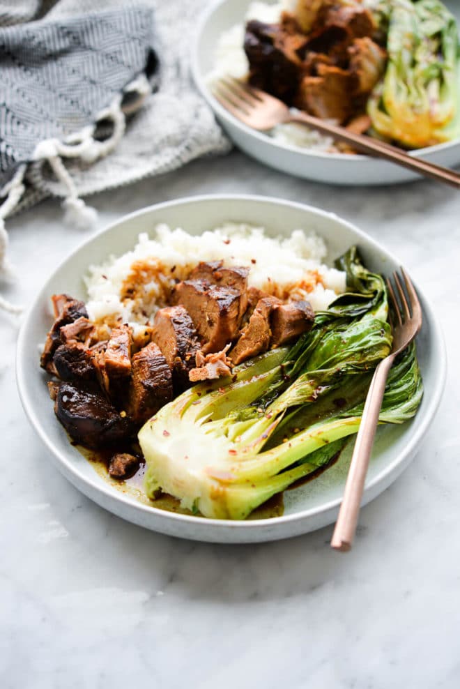 two shallow bowls of white rice, teriyaki pork tenderloin, and bok choy