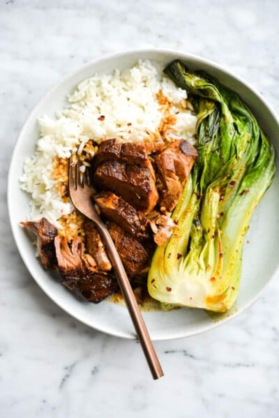 a shallow bowl of white rice, teriyaki pork tenderloin, and bok choy