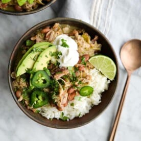 two bowls of pork chili verde over white rice on a marble surface