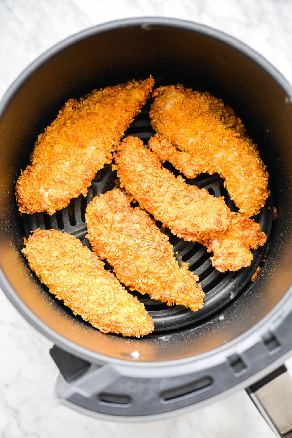 5 crispy chicken tenders in the basket of an air fryer