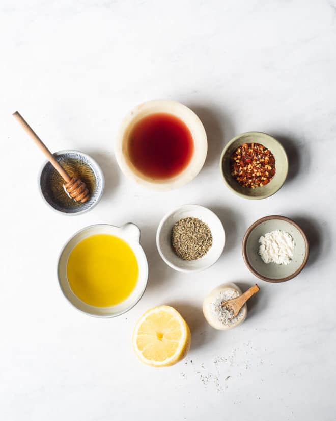 all of the ingredients for homemade italian dressing in different sized bowls and plates on a marble surface