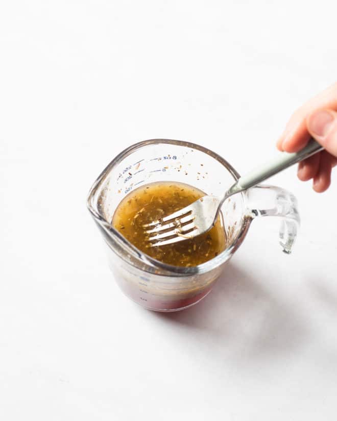 a person using a fork to whisk together a homemade Italian dressing