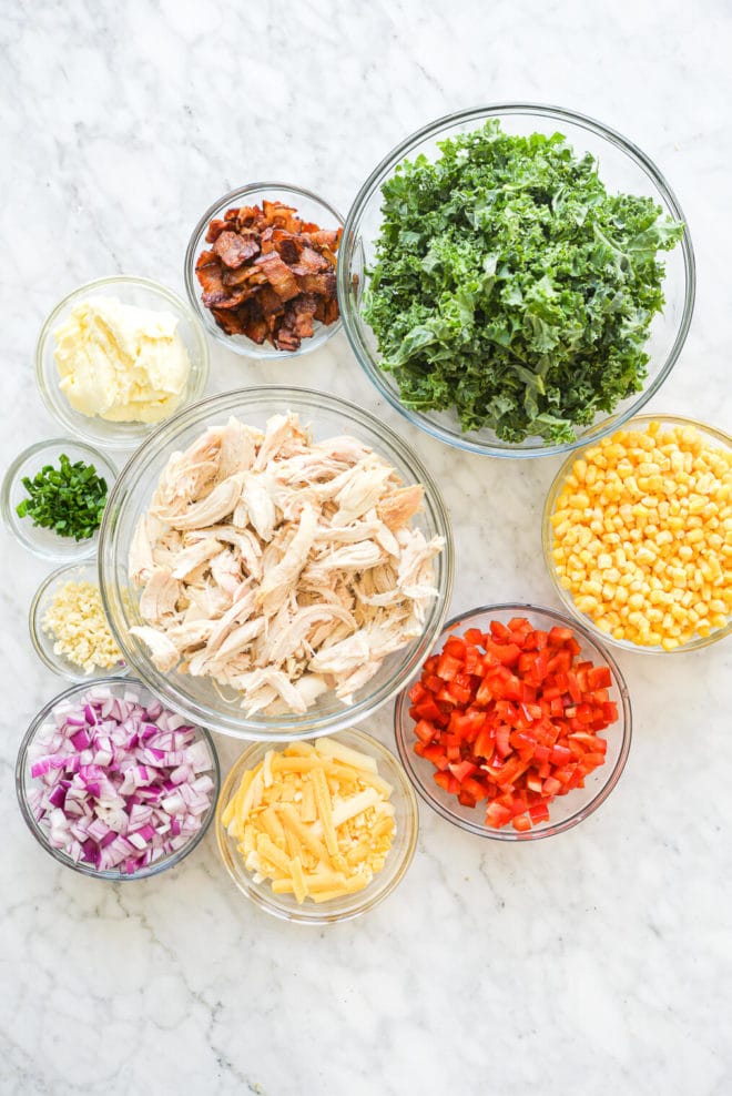 all of the ingredients for confetti chicken casserole in different sized bowls on a marble surface