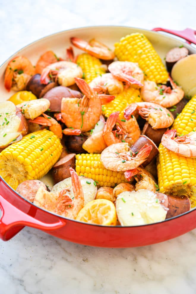 a large, shallow bowl of corn, shrimp, sausage, and potatoes (a shrimp boil)