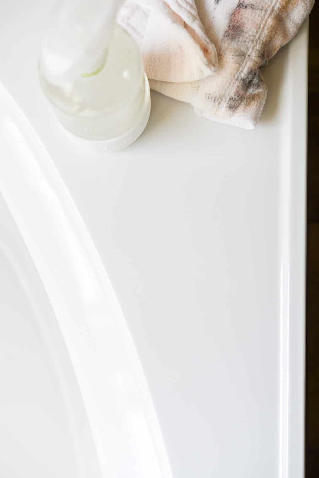 a bathroom tub that was covered in makeup smears now cleaned with a bottle of all purpose cleaner and a rag next to it