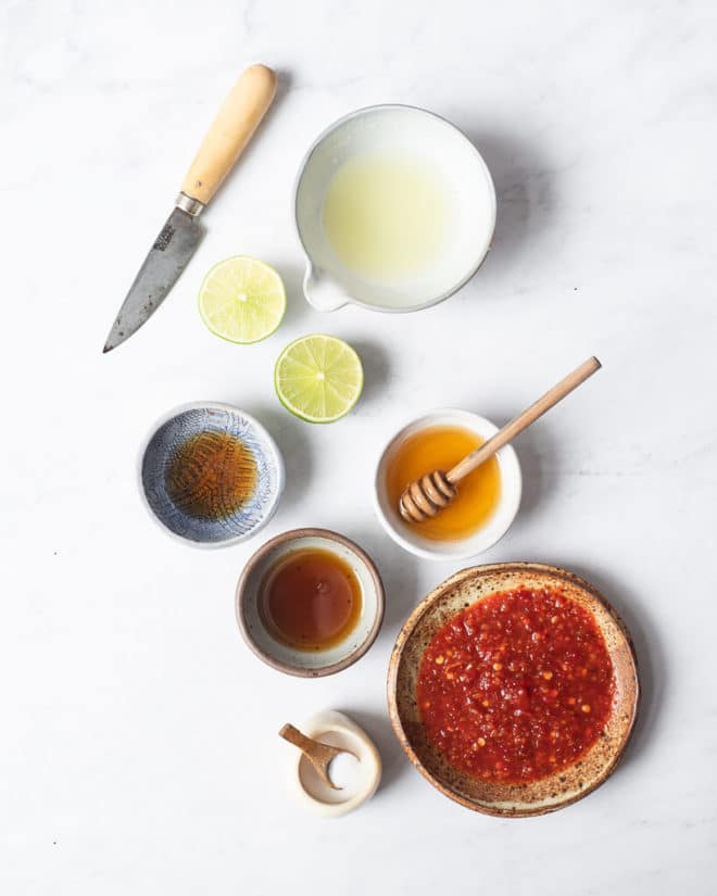 all of the ingredients for thai salad dressing in different sized bowls on a marble surface