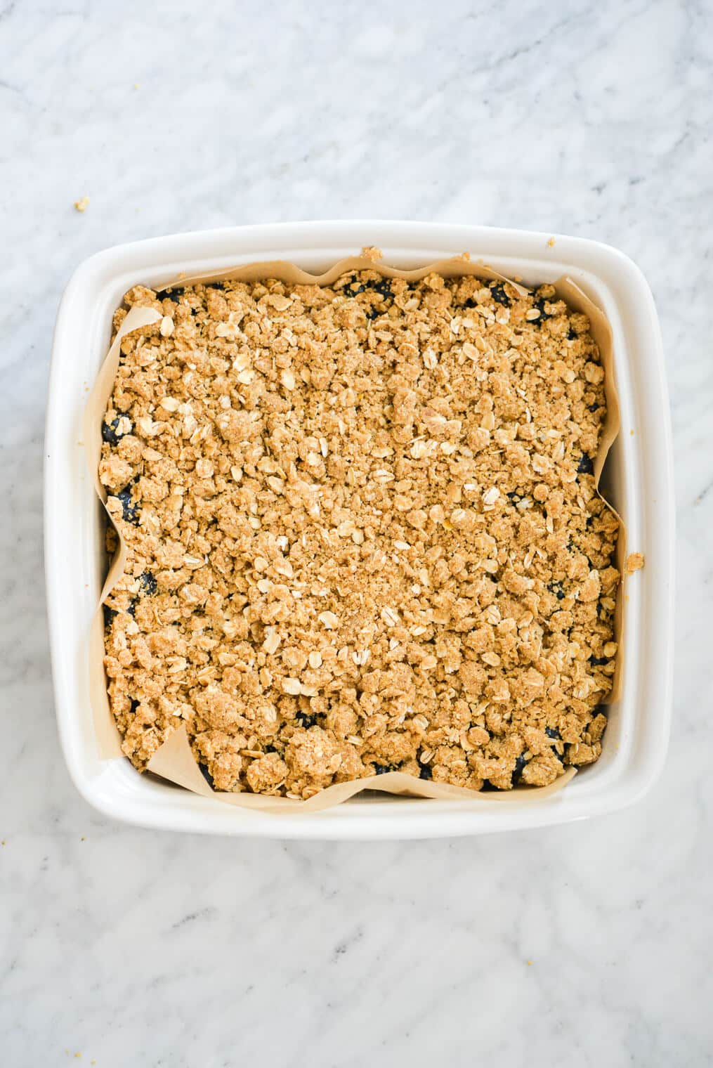 a top down shot of blueberry bars with a crumble on top in a square baking dish