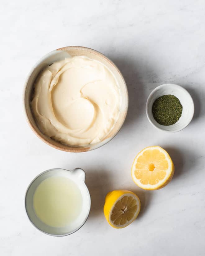 the ingredients for homemade ranch dressing in different sized bowls sitting on a marble surface