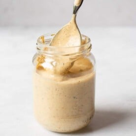 a person using a spoon to scoop out homemade remoulade sauce from a glass jar