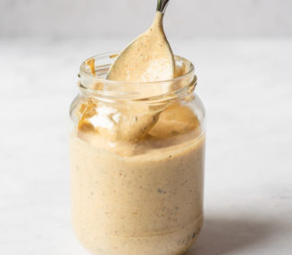 a person using a spoon to scoop out homemade remoulade sauce from a glass jar