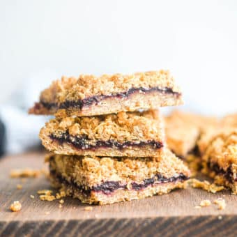 cut blueberry bars stacked on top of one another next to several other blueberry bars