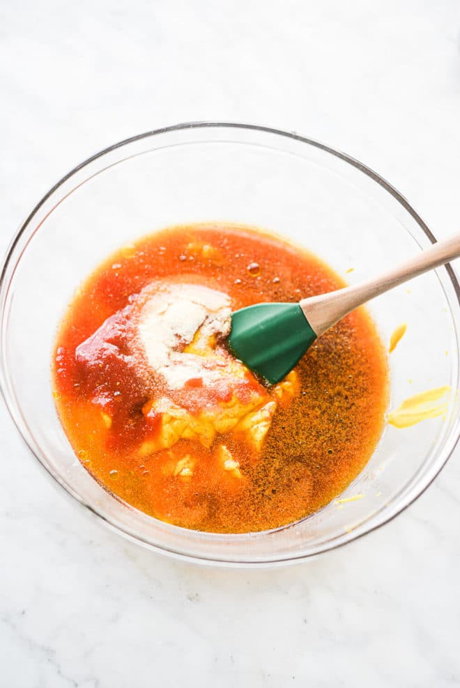 all of the ingredients for carolina BBQ sauce in a large glass bowl before being stirred together with a rubber spatula