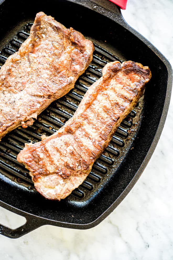 a skillet grill pan with seared steaks laying in it
