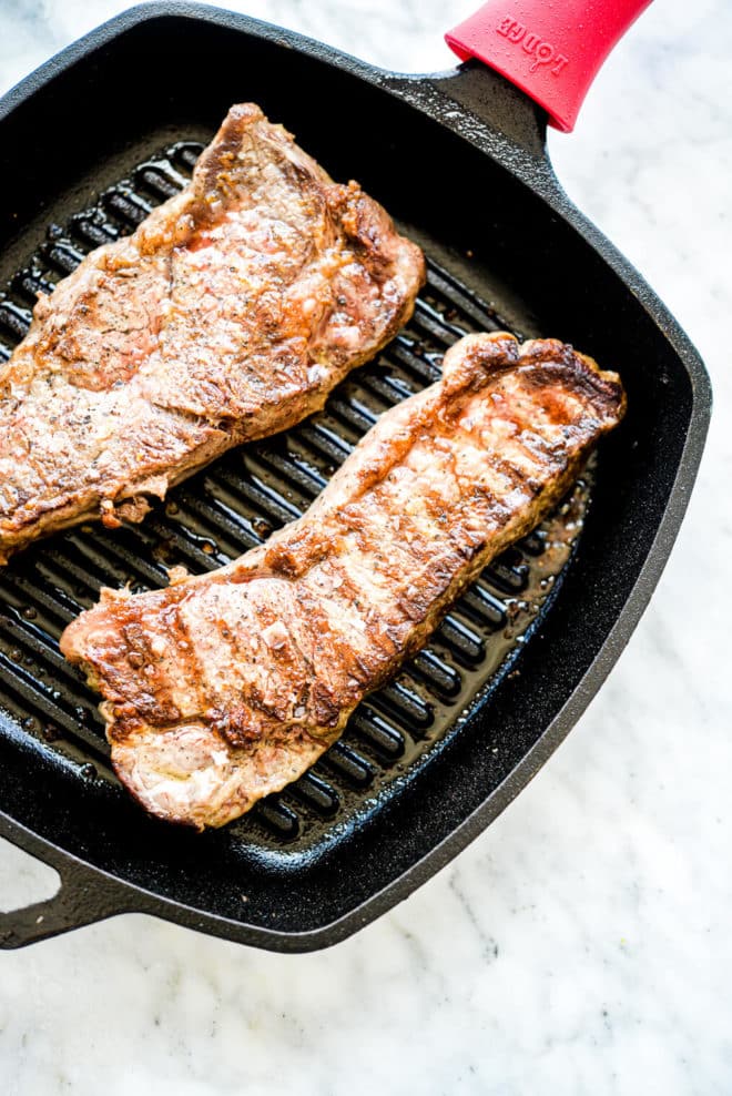 a grill pan with two cooked steaks laying in it