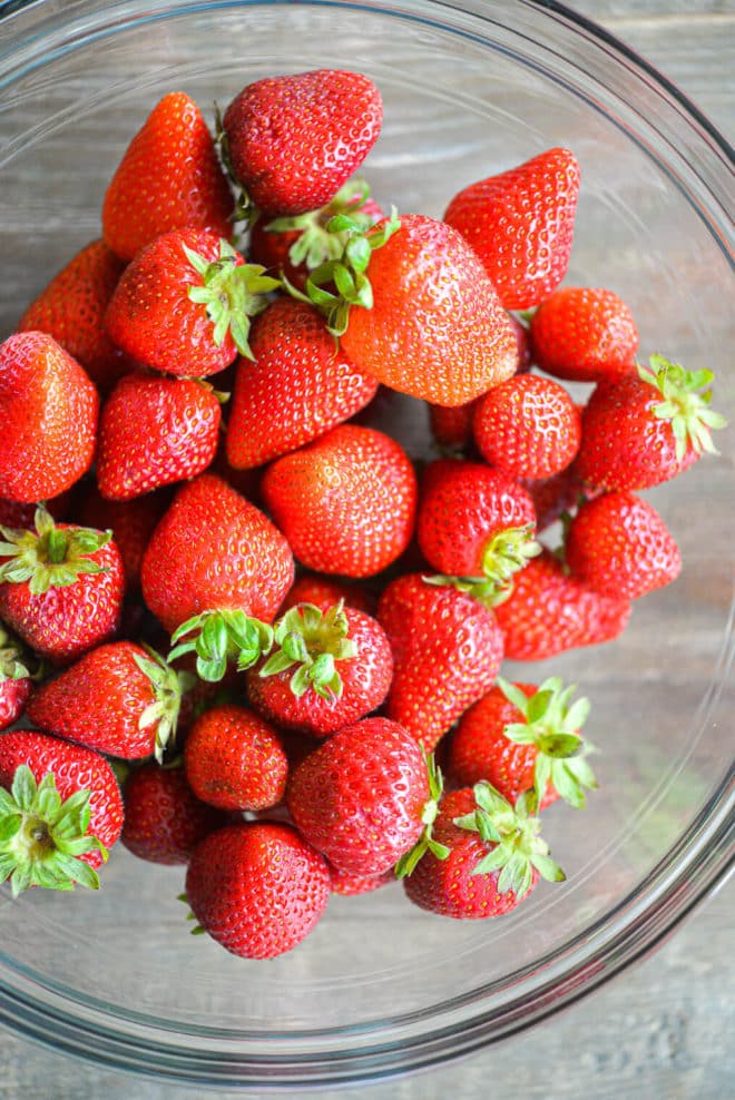 a large glass bowl of clean strawberries