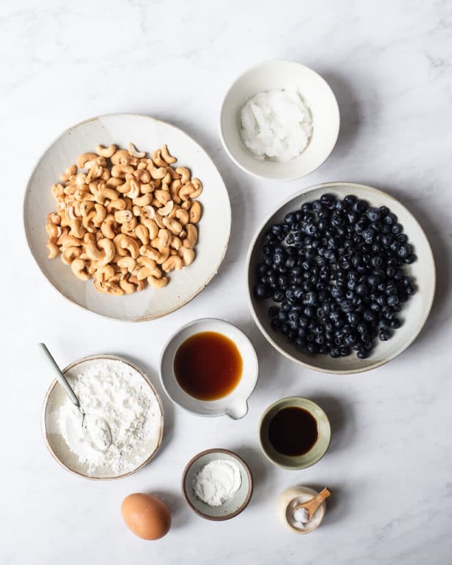 all of the ingredients for blueberry scones in different sized bowls on a marble surface