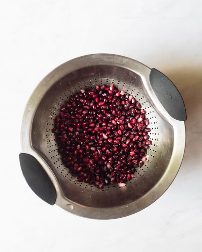pomegranate seeds in a strainer after being rinsed off
