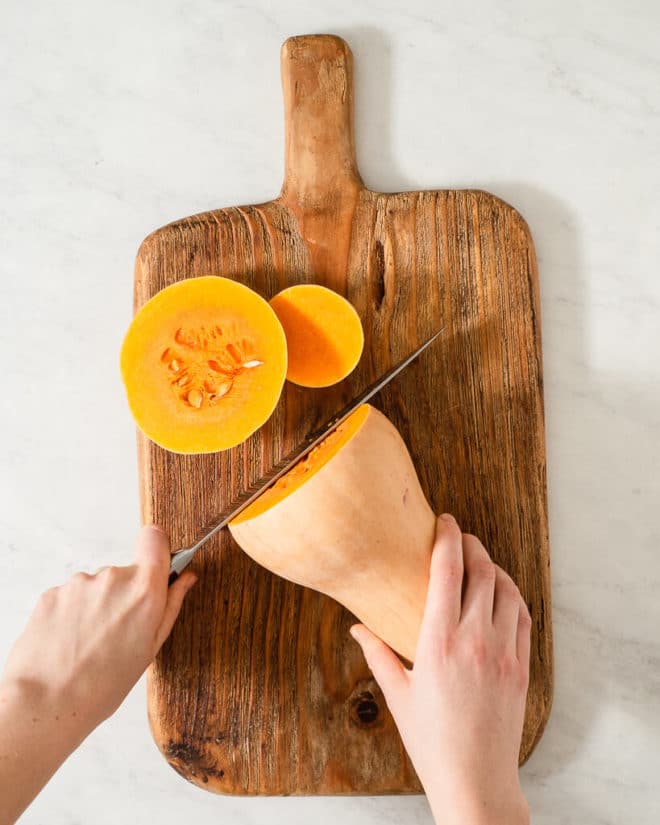 a person cutting the bottom off of a butternut squash