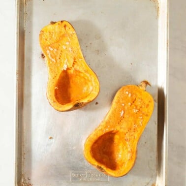 halved and roasted butternut squash on a sheet pan