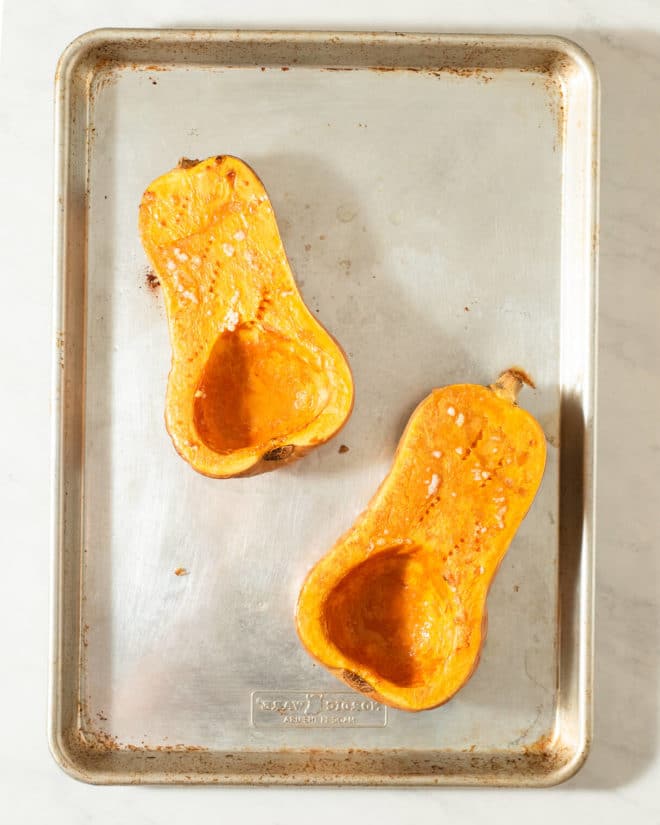 halved and roasted butternut squash on a sheet pan