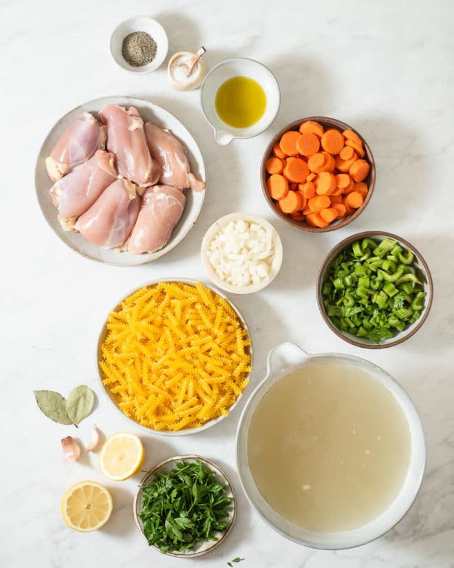 all of the ingredients for homemade chicken noodle soup on a marble surface