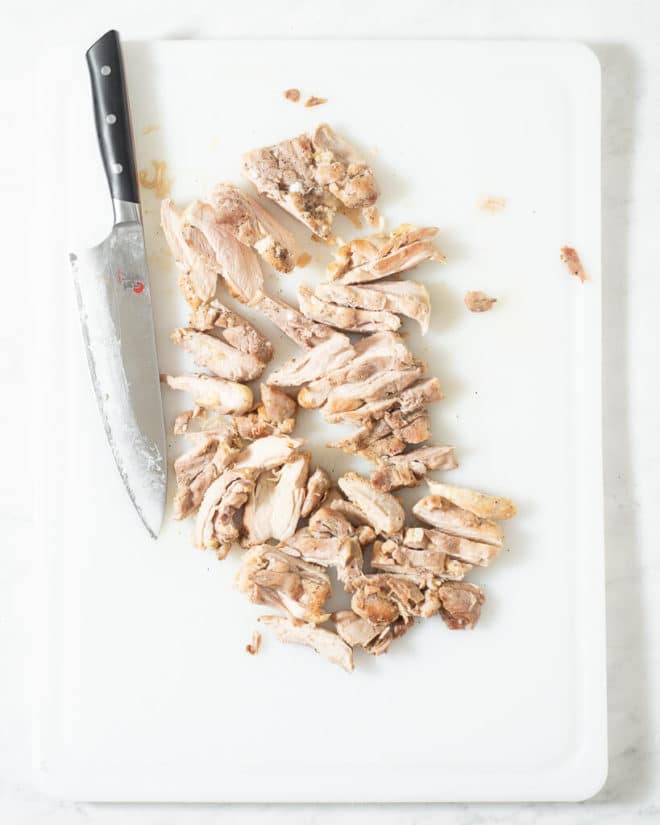 a person slicing chicken thighs for chicken noodle soup