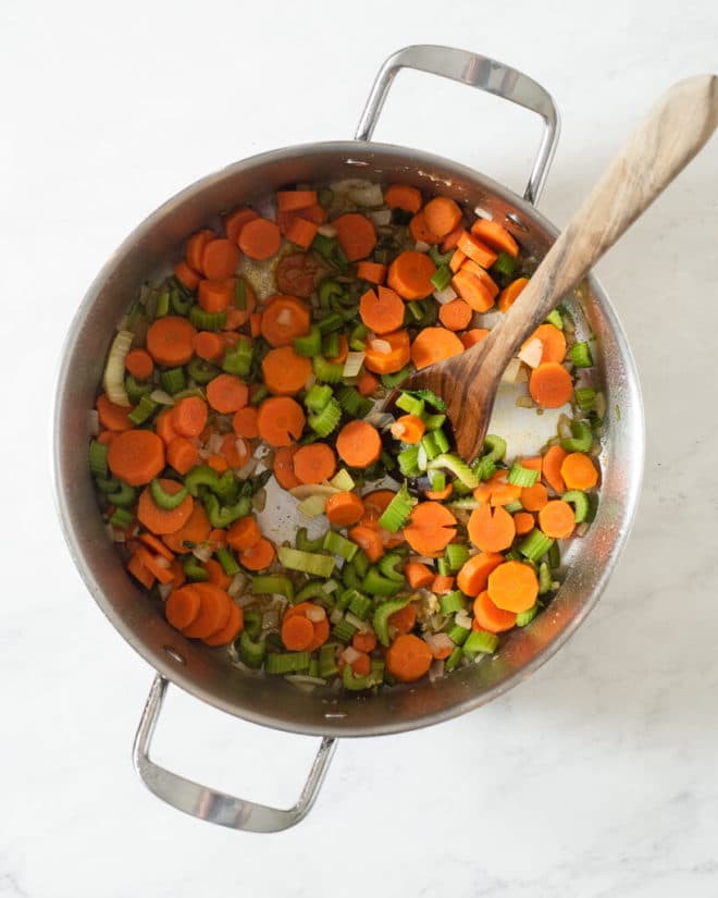 a large stainless steel pot of carrots and celery before becoming chicken noodle soup