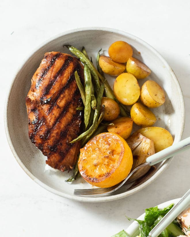 a grilled chicken breast, green beans, and baby potatoes on a plate