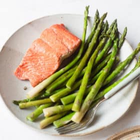 pan seared salmon and asparagus on a plate with a fork next to it