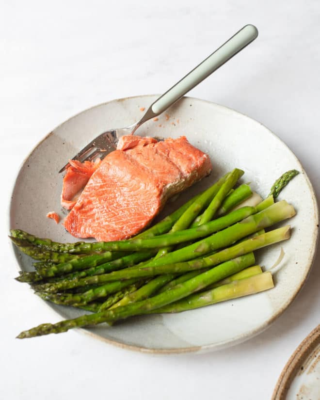 pan seared salmon and asparagus on a plate with a fork next to it