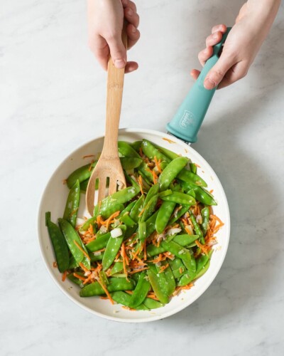 snow peas, carrots, and onions sauting in a pan