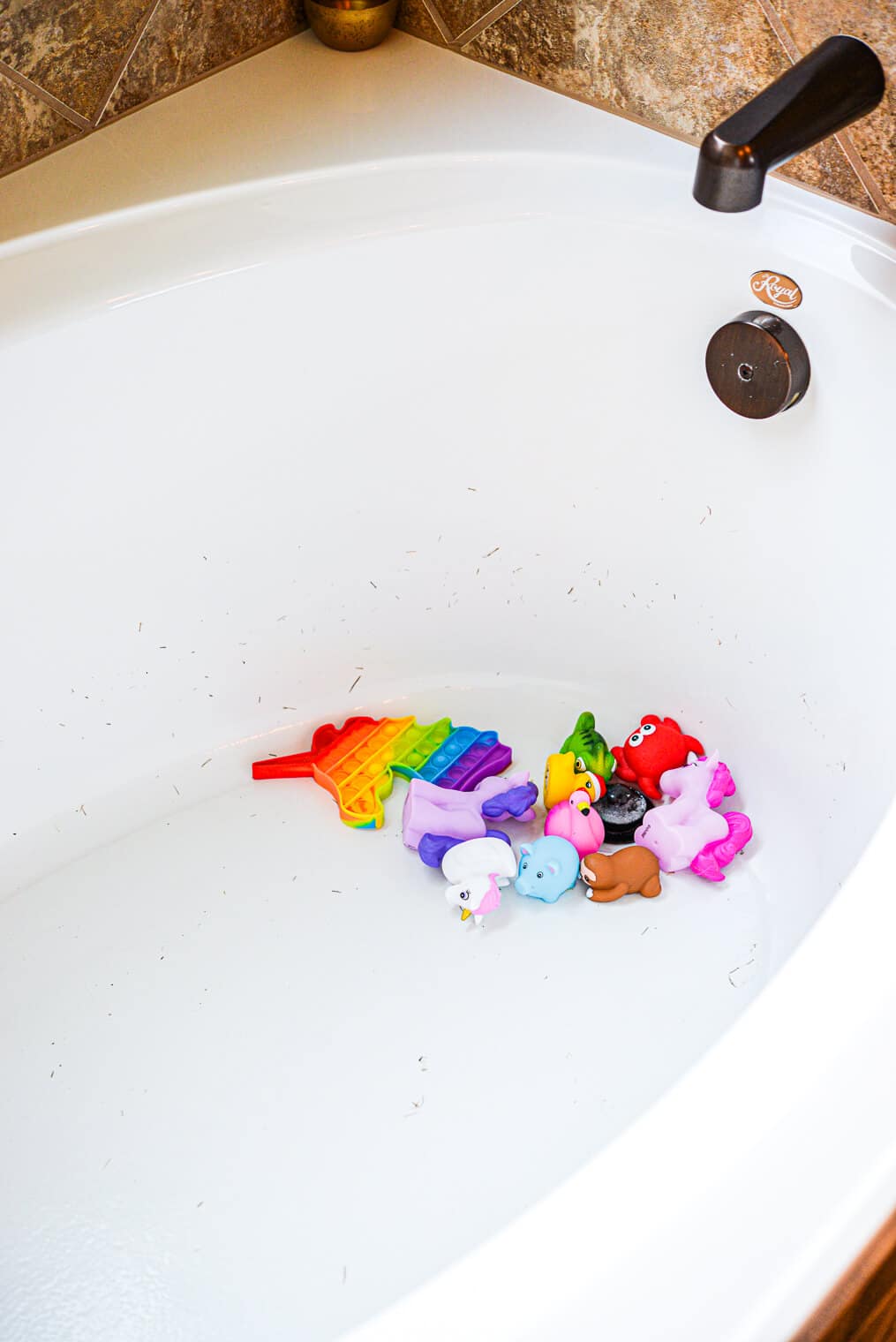 a dirty bathtub with colorful kids toys in it