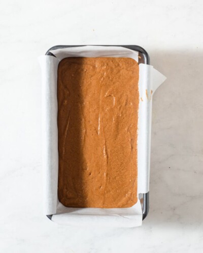 a loaf of healthy pumpkin bread (before being baked) in a parchment lined loaf pan