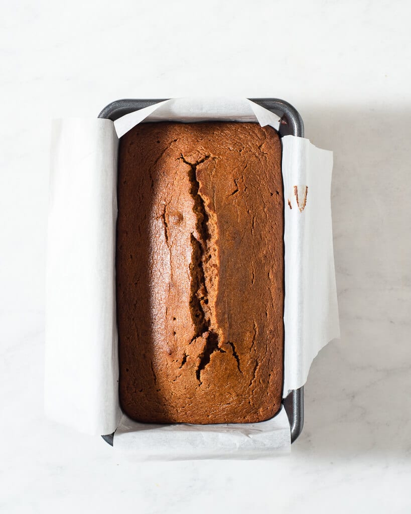 a loaf of healthy pumpkin bread in a parchment lined loaf pan