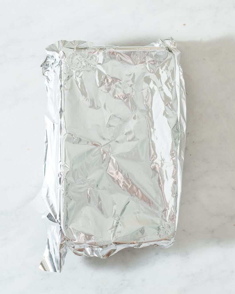 a loaf of keto pumpkin bread (before being baked) in a loaf pan covered with foil