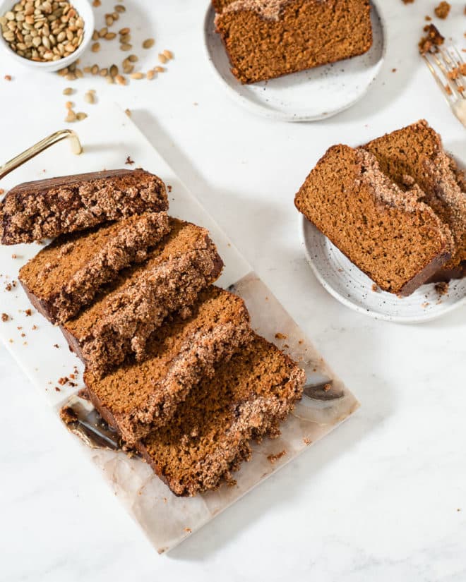 slices of keto pumpkin bread on plates next to a sliced loaf of keto pumpkin bread