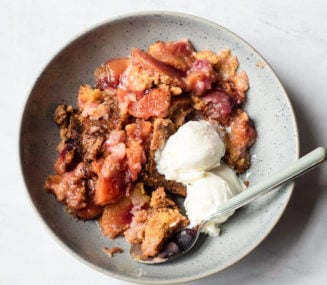 a serving of peach dump cake with two small scoops of vanilla ice cream