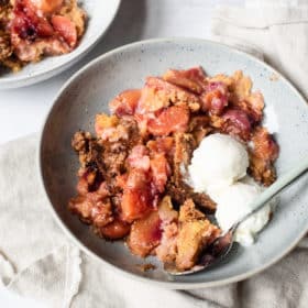 a serving of peach dump cake with two small scoops of vanilla ice cream