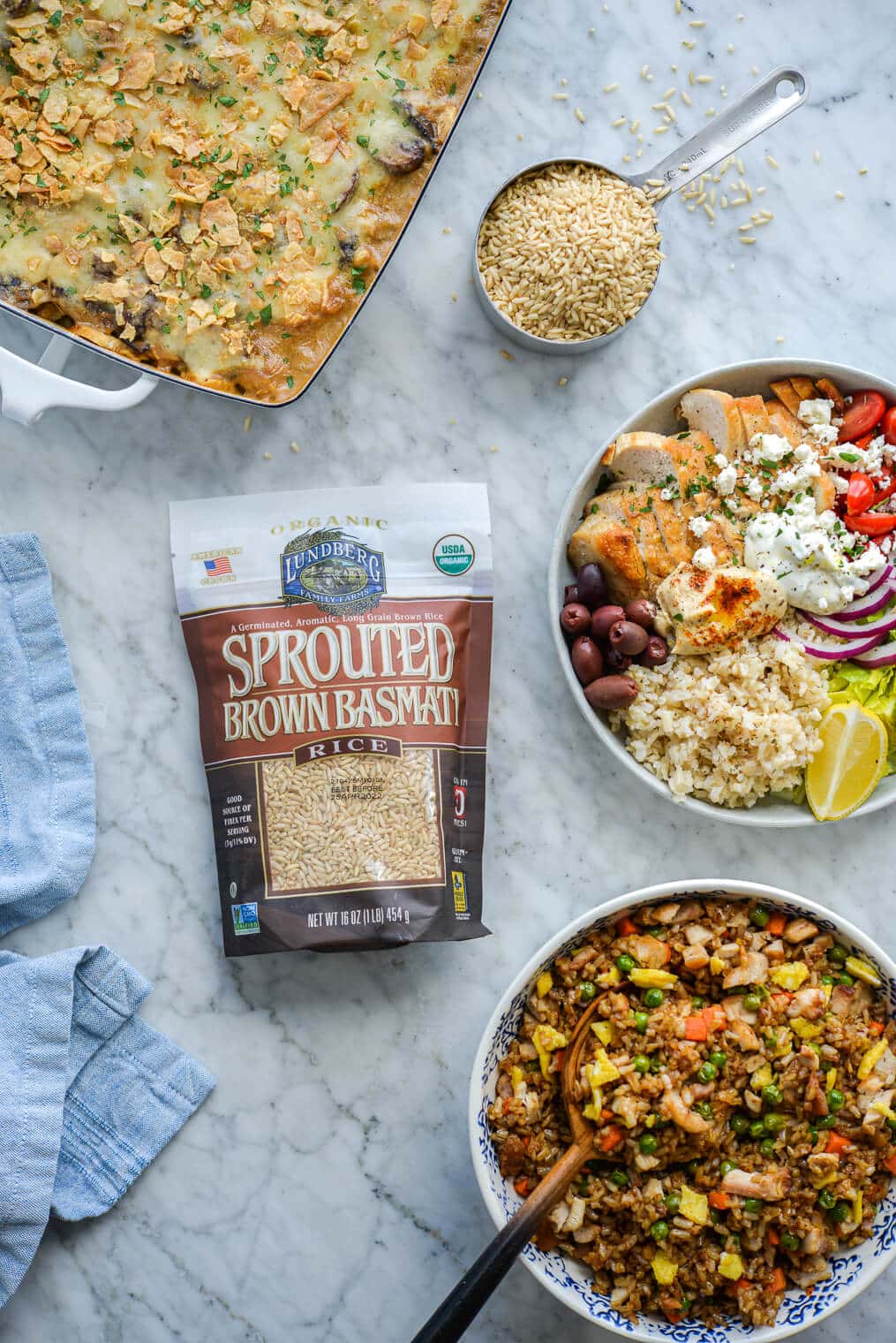 three chicken dishes (creamy chicken rice casserole, Greek power bowls, and chicken fried rice) surrounding a bag of Lundberg's sprouted brown basmati rice