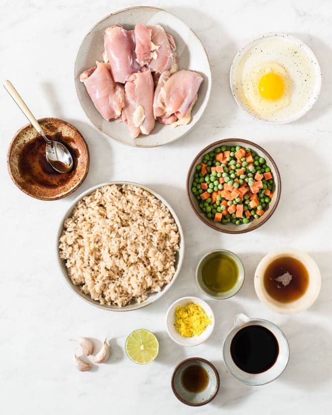 all of the ingredients for chicken fried rice in different sized bowls on a marble surface