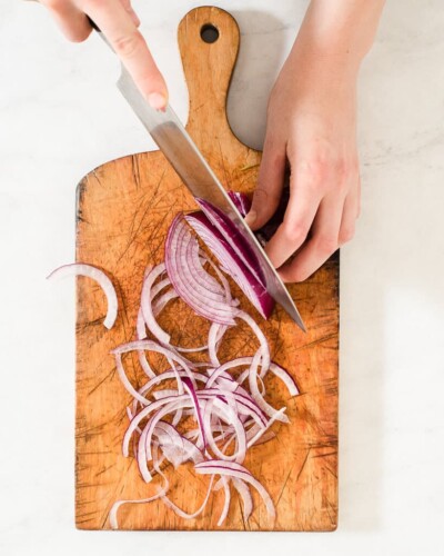 a person slicing purple onions on a cutting board