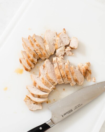 sliced chicken on a cutting board next to a knife
