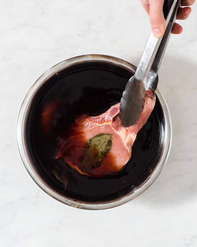 pork chops brining in a large metal bowl