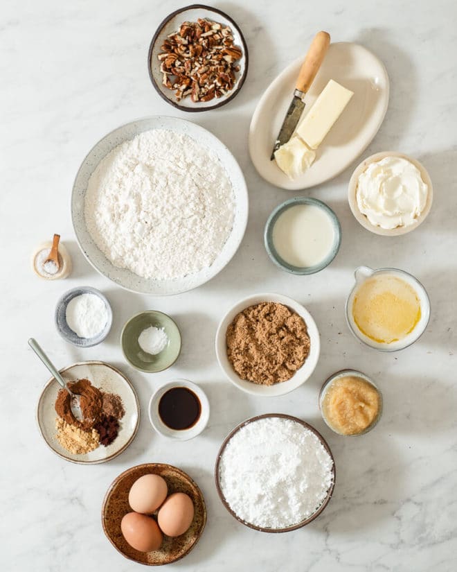 all of the ingredients for spice cake in different sized bowls on a marble surface