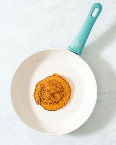 a pumpkin pancake cooking on a green life pan