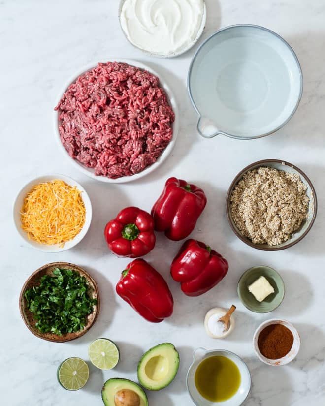 all of the ingredients for tex mex stuffed peppers in different sized bowls and plates on a marble surface