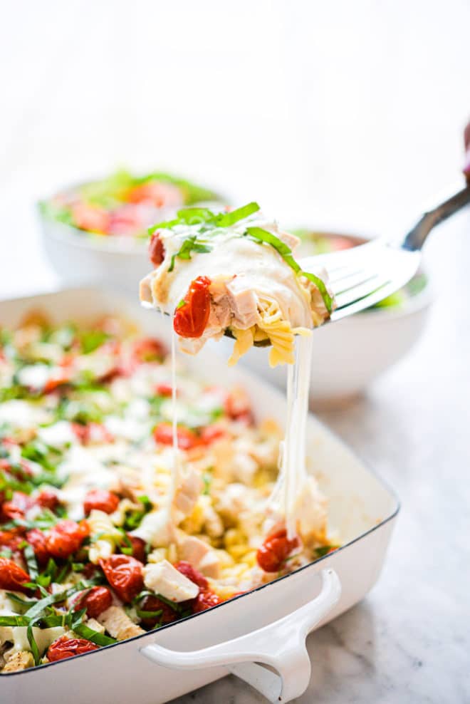 a serving of caprese chicken casserole being scooped out with a spatula