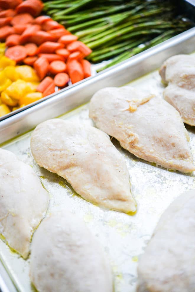 two sheet pans -- one with baked chicken breasts and one with roasted veggies
